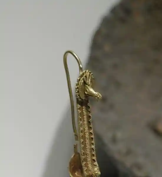 Gold earrings with a diamond pendant that looks like a 3D cross